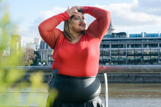 retrato de una joven mujer latina de talla grande y de moda vestida de rojo al aire libre mirando hacia un lado