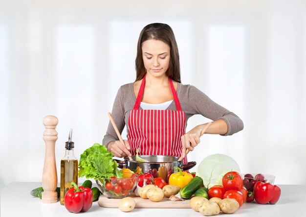 Retrato de joven mujer linda con comida en el fondo de la cocina