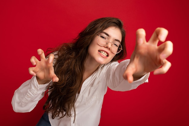 Foto retrato de joven mujer morena bonita emocional con camisa blanca casual y gafas ópticas