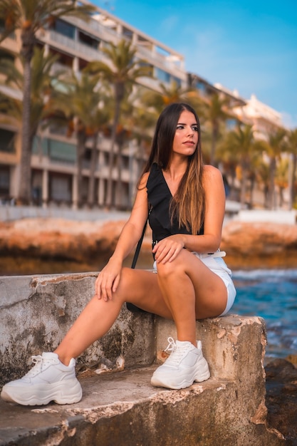 Retrato de una joven mujer morena disfrutando de su día en la costa junto a la playa