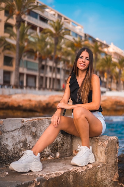 Retrato de una joven mujer morena disfrutando de su día en la costa junto a la playa