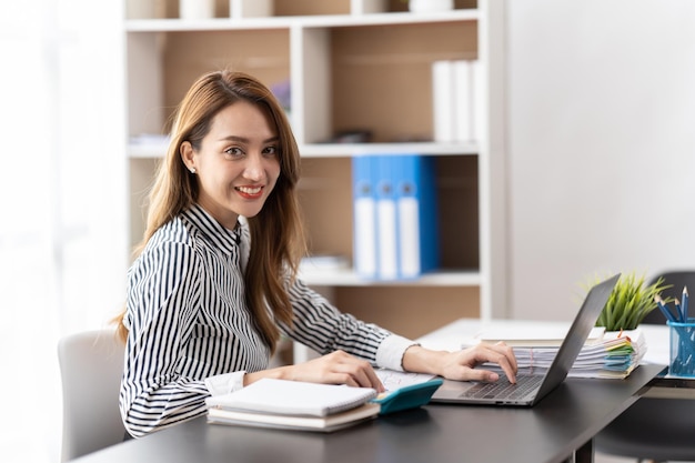 Retrato de una joven mujer de negocios asiática feliz de trabajar en la oficina moderna usando una computadora portátil empleado de negocios freelance marketing en línea comercio electrónico concepto de telemarketing