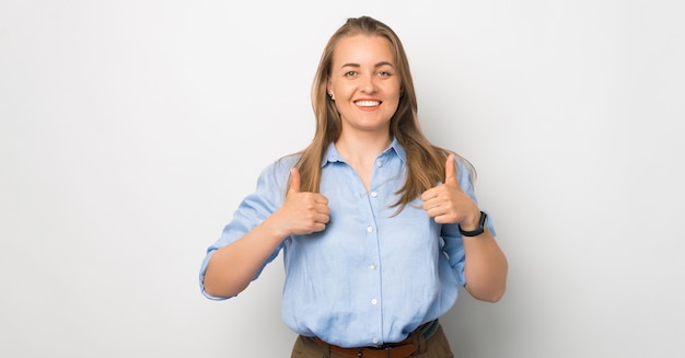 Retrato de joven mujer de negocios en casual mostrando Thumbs up sobre fondo blanco.