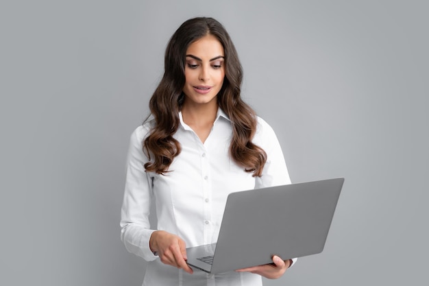 Retrato de una joven mujer de negocios feliz con una laptop sobre fondo gris