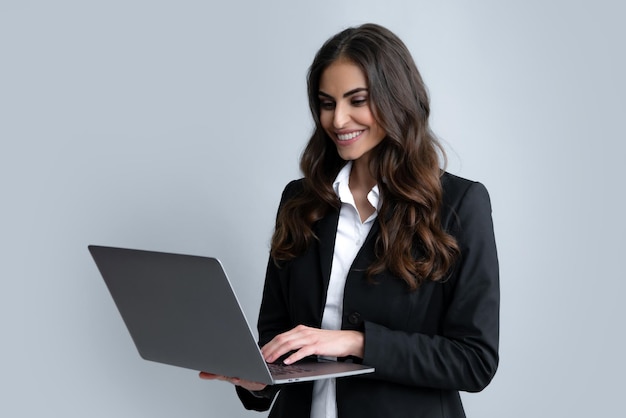 Retrato de una joven mujer de negocios feliz con una laptop sobre fondo gris