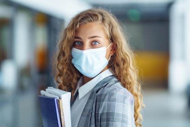 Retrato de una joven mujer de negocios con mascarilla protectora en la oficina Mujer emprendedora COVID 19