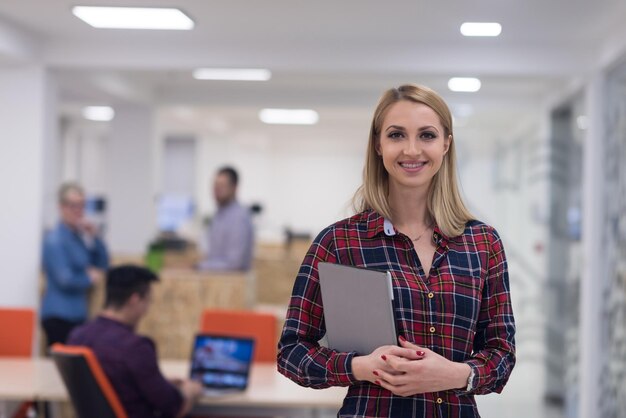 retrato de una joven mujer de negocios en el moderno interior de la oficina de inicio, equipo reunido en segundo plano