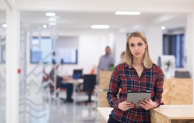 retrato de una joven mujer de negocios en el moderno interior de la oficina de inicio, equipo reunido en segundo plano