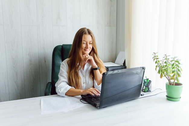 Retrato de una joven mujer de negocios con ordenador portátil en la oficina