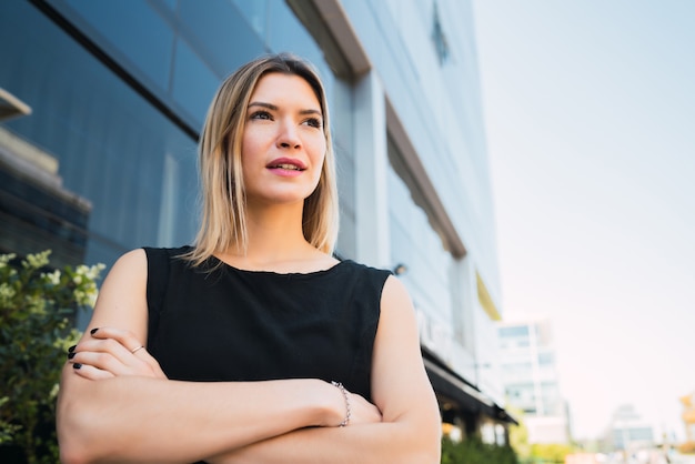 Retrato de joven mujer de negocios de pie fuera de los edificios de oficinas