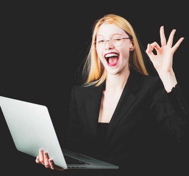 Retrato joven mujer de negocios sorprendida guiñando un ojo delante de la computadora portátil mirando a la cámara Funny fa