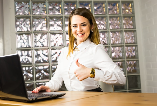 Foto retrato joven mujer de negocios trabajando en una oficina moderna. pulgar arriba.