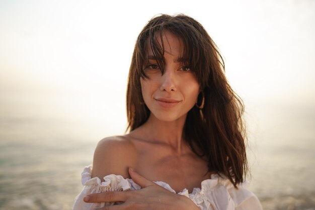 Retrato de joven mujer de pelo morena en la playa al atardecer