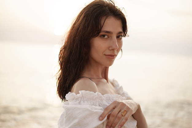 Retrato de joven mujer de pelo morena en la playa al atardecer