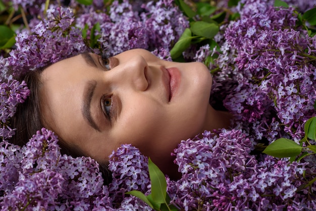 Retrato de una joven mujer rodeada de lilas.