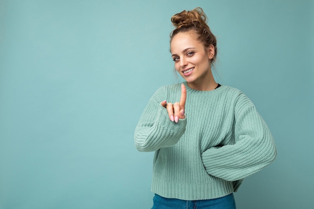 Retrato de joven mujer rubia atractiva positiva feliz con emociones sinceras vistiendo casual jersey azul