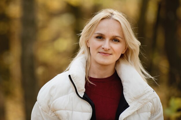 Retrato de una joven mujer rubia en el bosque de otoño.