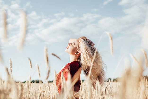 Retrato de joven mujer rubia en campo de trigo en verano