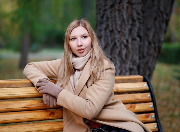 Retrato de una joven mujer rubia hermosa en un abrigo beige