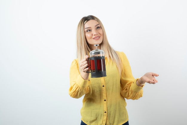 Retrato de joven mujer rubia con tetera mirando en algún lugar