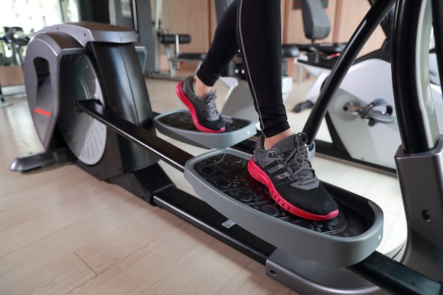 Retrato de joven mujer sana y deportiva con máquina de ejercicio en el gimnasio