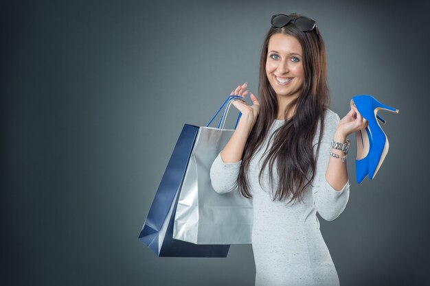 Retrato de joven mujer sonriente feliz con bolsas de compras, tarjeta de crédito y zapatos.