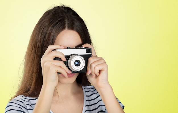 Retrato de una joven mujer sonriente filmando con cámara retro aislada