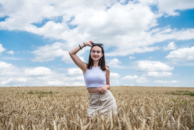 Retrato de joven mujer sonriente de pie en el campo de trigo. Niña feliz libre