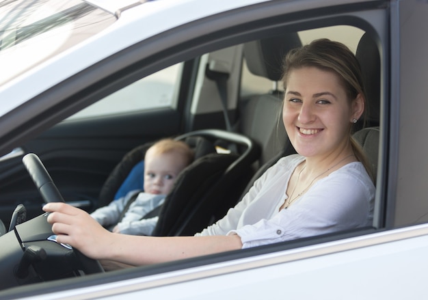 Retrato, de, joven, mujer sonriente, posar, en coche, con, ella, nene