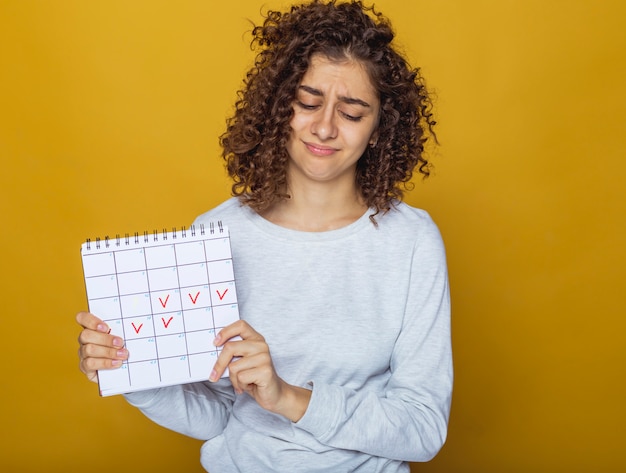 Retrato de una joven mujer sosteniendo un calendario con días marcados