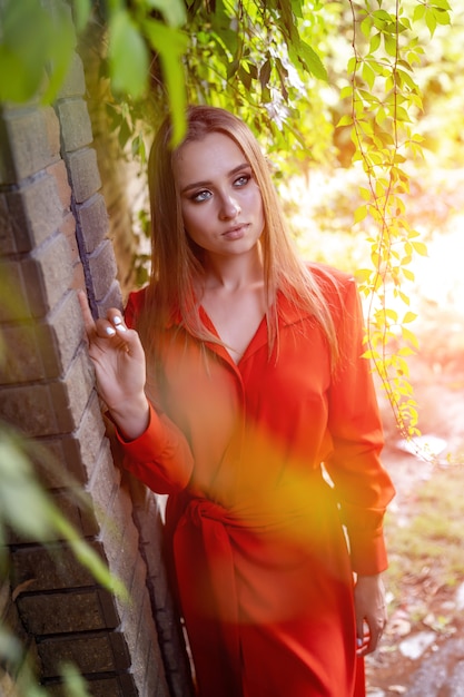 Retrato de una joven mujer en vestido largo rojo posando al aire libre