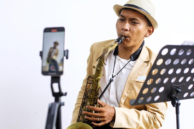 Foto retrato de un joven músico asiático que graba usando su teléfono inteligente para el contenido de las redes sociales