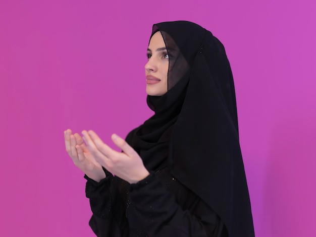 Retrato de una joven musulmana haciendo dua. Niña árabe con abaya mantiene las manos en gesto de oración. Representando la adoración a Dios y el concepto de Ramadan Kareem