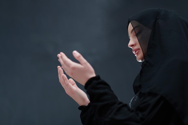 Retrato de una joven musulmana haciendo dua. Niña árabe con abaya mantiene las manos en gesto de oración. Representando la adoración a Dios y el concepto de Ramadan Kareem