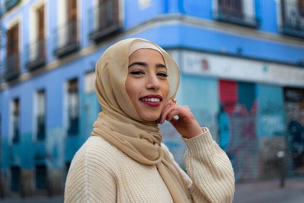 Retrato de una joven musulmana con hiyab mirando a la cámara con fondo azul