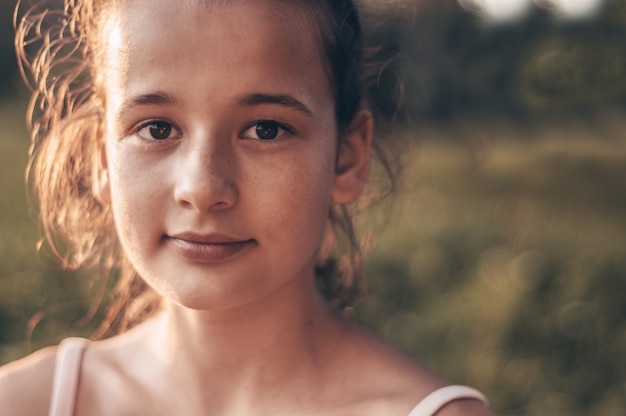 Retrato de joven muy hermosa en el sol de la tarde en la naturaleza. chica disfrutando de verano y clima soleado en la pradera.