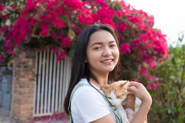 retrato, joven, niña asiática, con, un, gato, al aire libre, hermoso, flor, plano de fondo