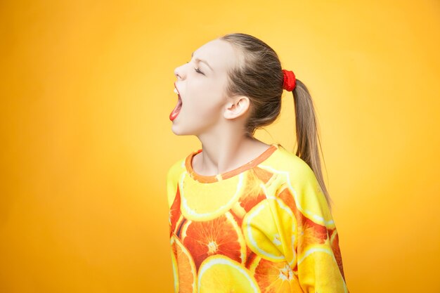 Retrato de joven niña gritando bastante divertido vistiendo sudadera estampada naranja