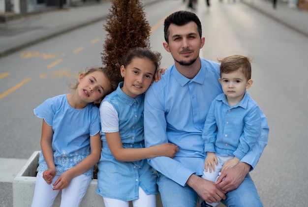 Retrato de un joven padre de familia feliz con tres hijos al aire libre