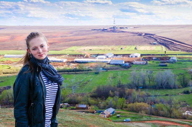 Retrato de una joven en el paisaje rural con plataformas de perforación en el campo