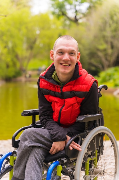 Retrato de un joven paralizado en un parque público de la ciudad Sentado en la silla de ruedas sonriendo mirando a la cámara