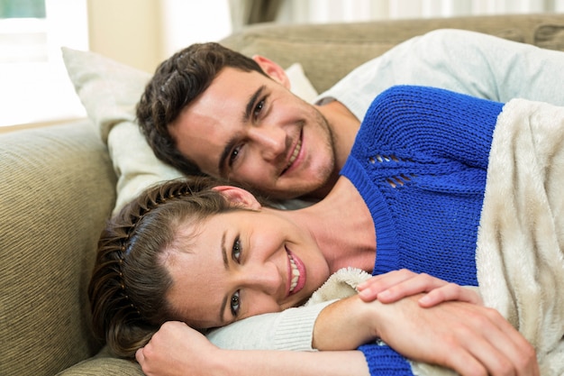 Retrato de la joven pareja acostado juntos en el sofá y sonriendo