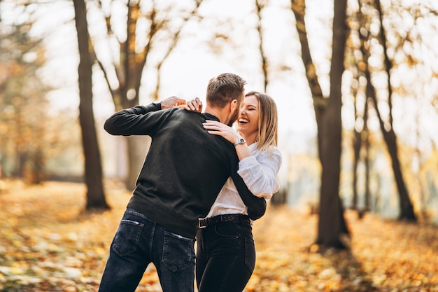 Retrato de una joven pareja amorosa. Hombre y mujer abrazándose y sonriendo en el fondo del parque otoño