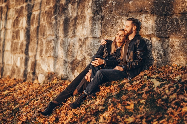 Retrato de una joven pareja amorosa, sentada en la hoja de otoño y disfrutando de la naturaleza