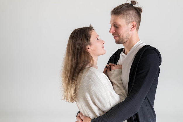 Retrato de una joven pareja caucásica de amantes abrazándose y mirándose en un fondo blanco