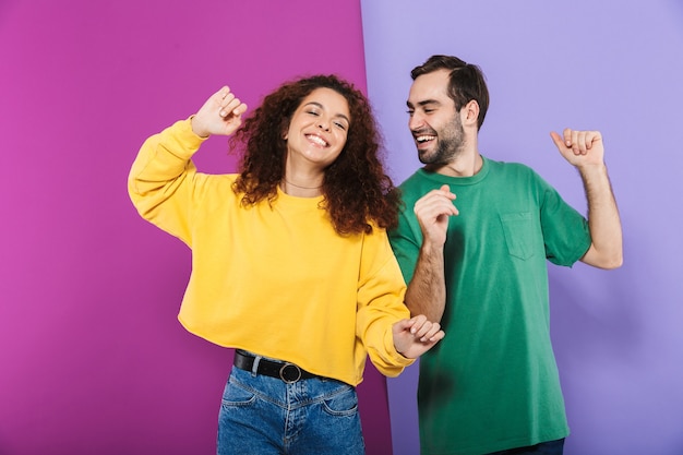 Retrato de joven pareja caucásica hombre y mujer en ropa colorida divirtiéndose y bailando juntos aislado