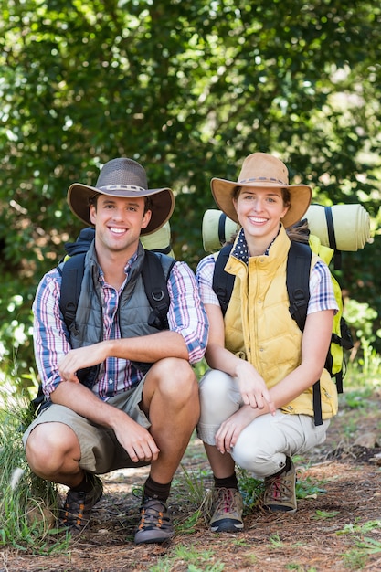 Foto retrato de la joven pareja en cuclillas en el bosque