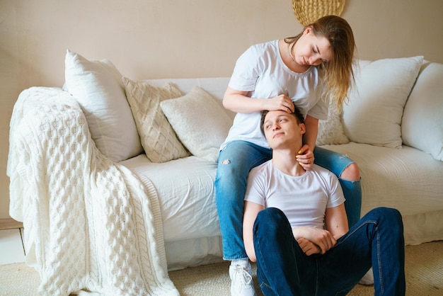 Retrato de una joven pareja emocional abrazándose chico y chica abrazando chica sentada en el sofá g ...