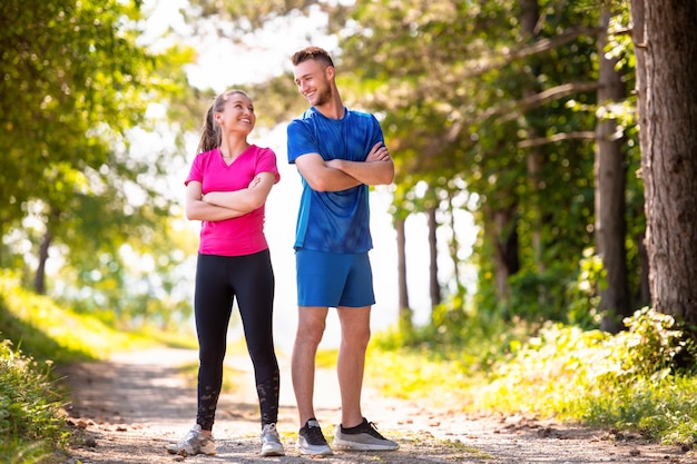 retrato de una joven pareja feliz disfrutando de un estilo de vida saludable mientras trota en un camino rural a través del hermoso bosque soleado, el ejercicio y el concepto de fitness