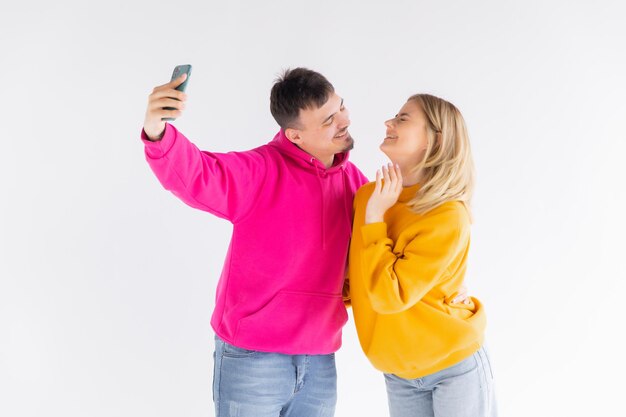 Retrato de una joven pareja feliz mostrando los pulgares hacia arriba mientras se toman un selfie juntos